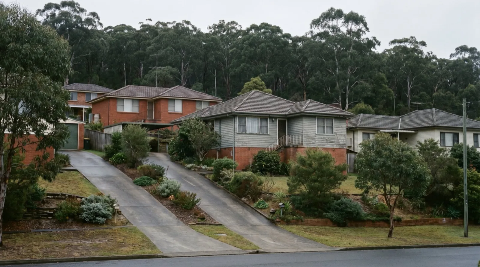 Steep twin driveways climbing to houses on a bushland-edge street in Kahibah